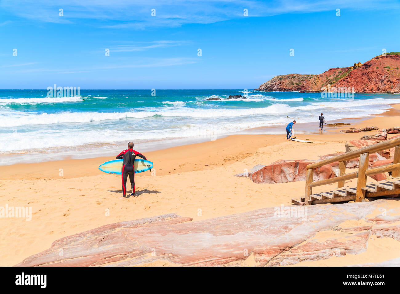 PRAIA DO AMADO BEACH, PORTUGAL - MAY 15, 2015: People surfing on Praia do Amado beach with ocean waves hitting shore. Algarve region is popular holida Stock Photo