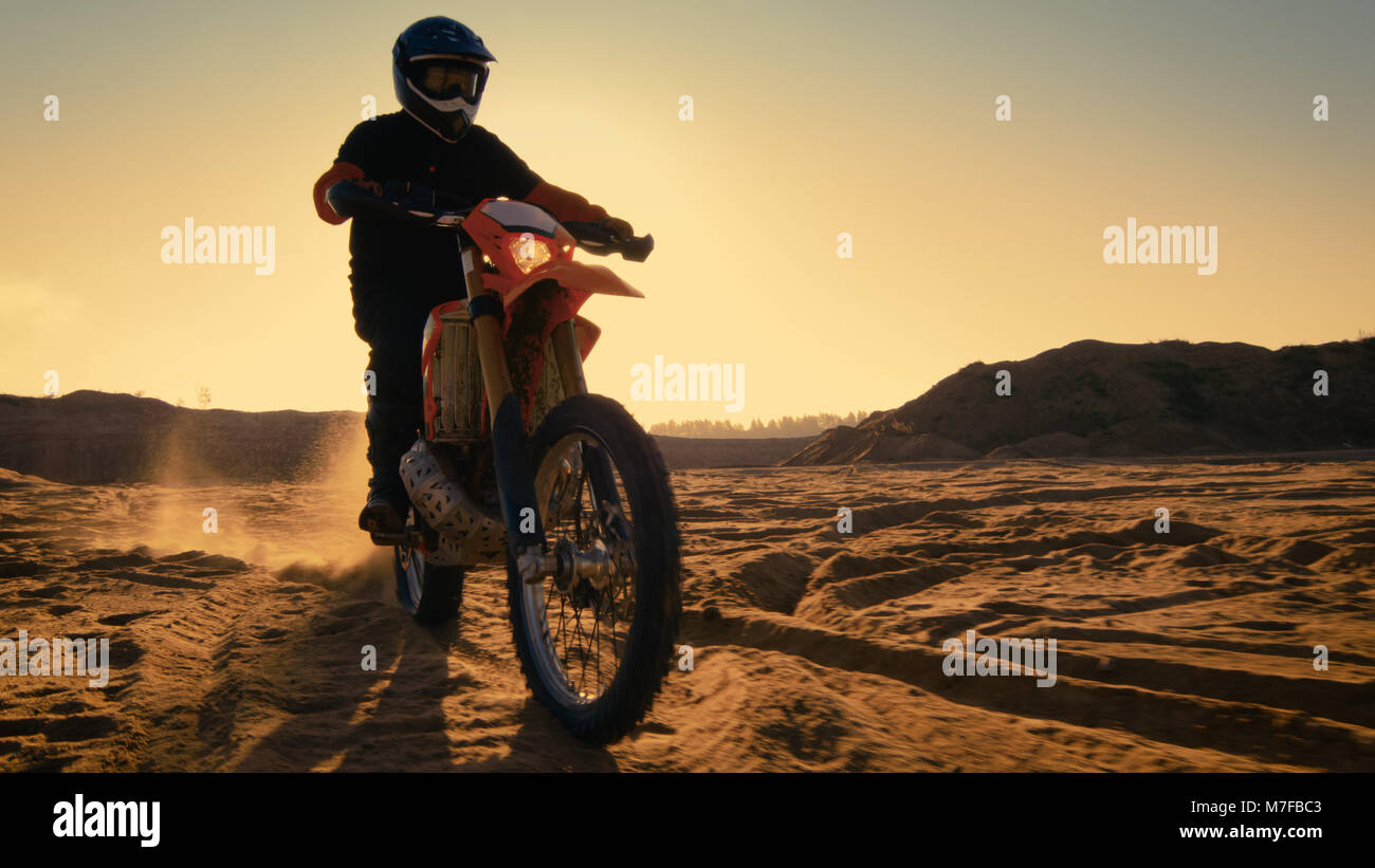 Following Shot of the Professional Motocross Driver Riding on His FMX Motorcycle on the Extreme Off-Road Terrain Track. Stock Photo