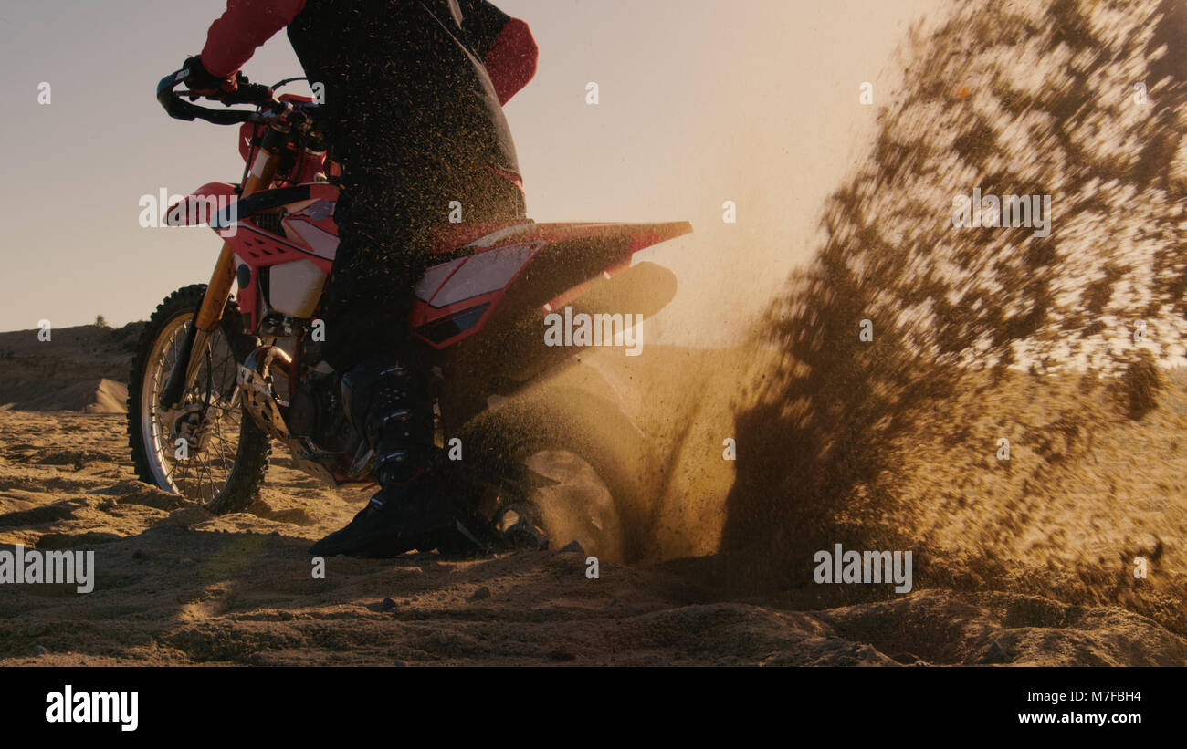 Back View Footage of the Professional Rider on the FMX Dirt Bike Twisting Full Throttle Handle and Digging into the Sand with His Back Wheel. Stock Photo