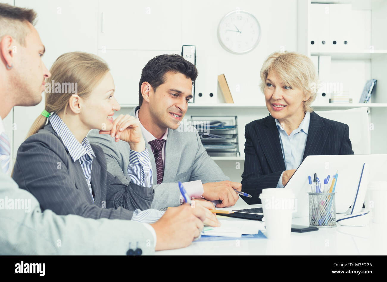Smiling business partners discussing projects and ideas at meeting in ...