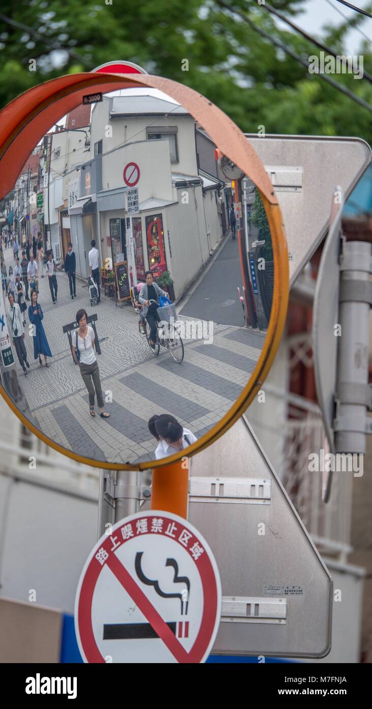 Reflection of typical Tokyo street scene in oval traffic mirror. Stock Photo