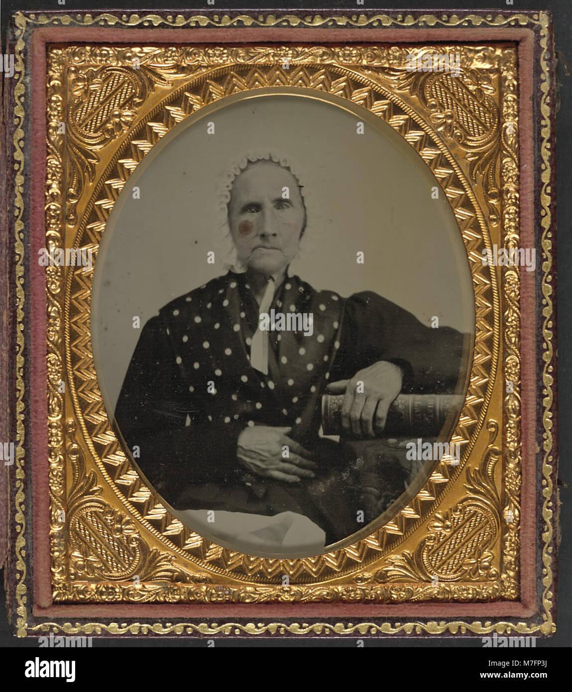 An unidentified woman is seen resting her arm on a book titled 'History of Slavery,' suggesting a connection to historical studies on slavery and its legacy. Stock Photo