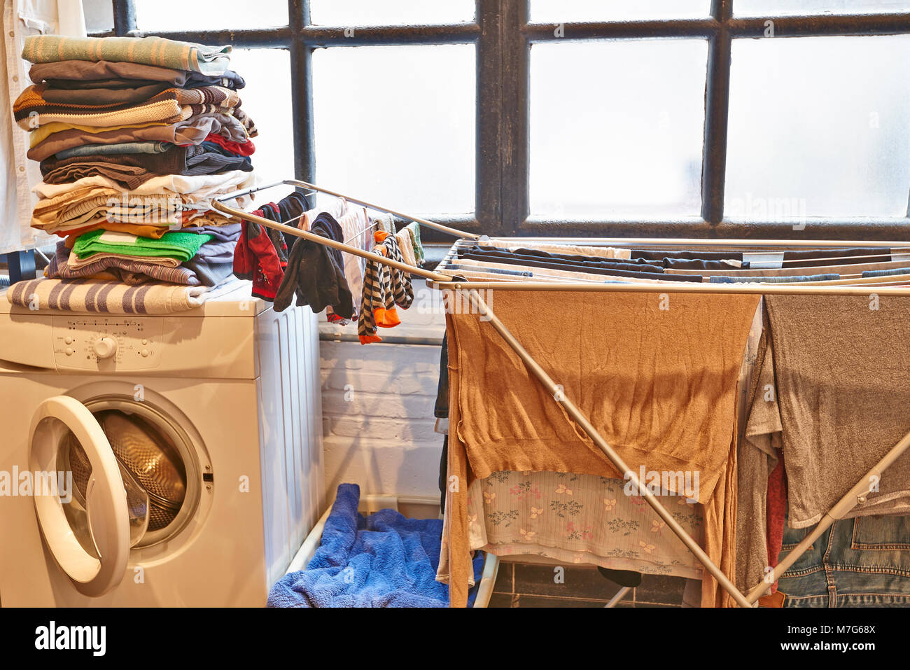 Untidy and messy male laundry room against windows Stock Photo