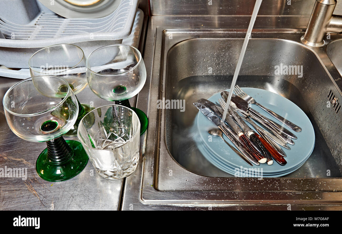 Dirty plates and cutlery in kitchen sink before washing Stock Photo