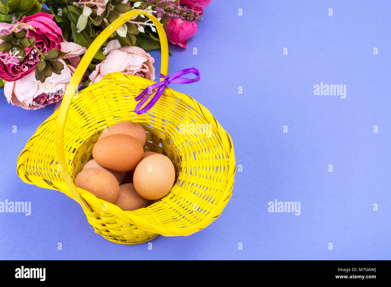 Preparation for Easter. Yellow basket with chicken eggs on violet