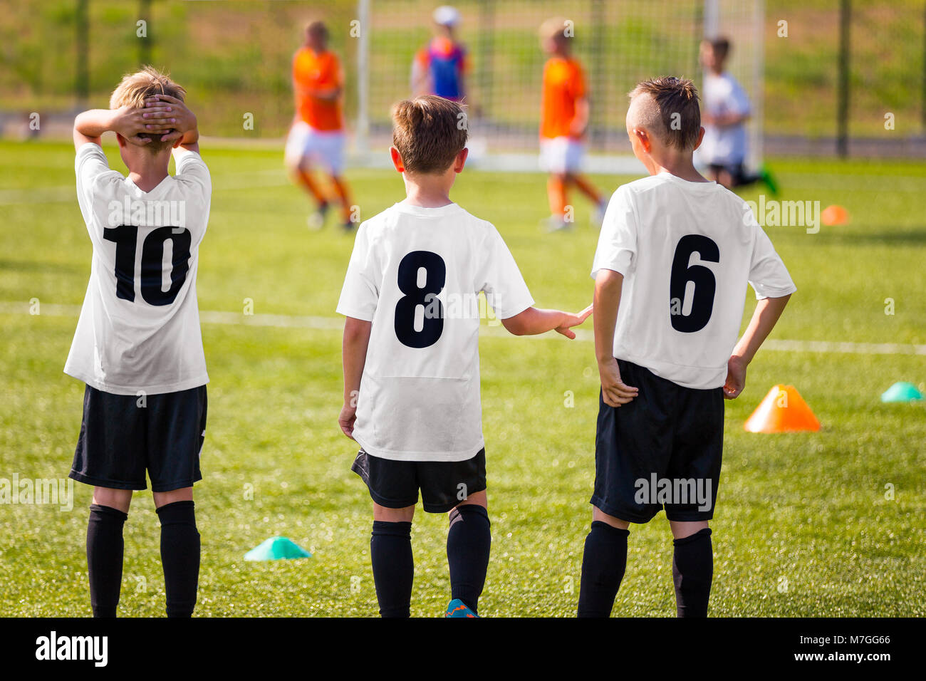 Children Football Team. Young Boys Watching Soccer Match. Football Tournament Competition in the Background. KidsFootball Team Players on Summer Sport Stock Photo
