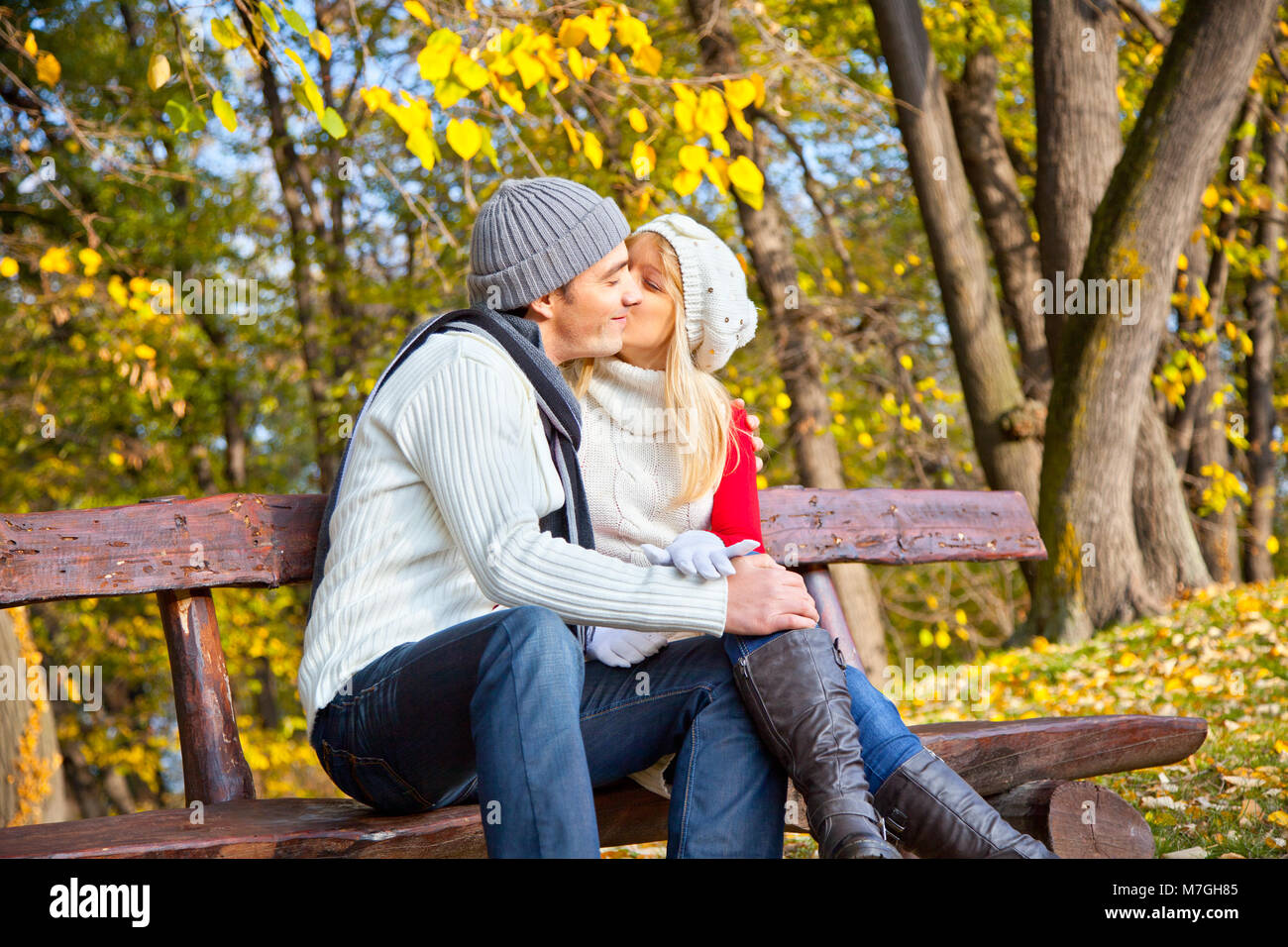 Young romantic couple on a bench in park. Autumn set Stock Photo - Alamy
