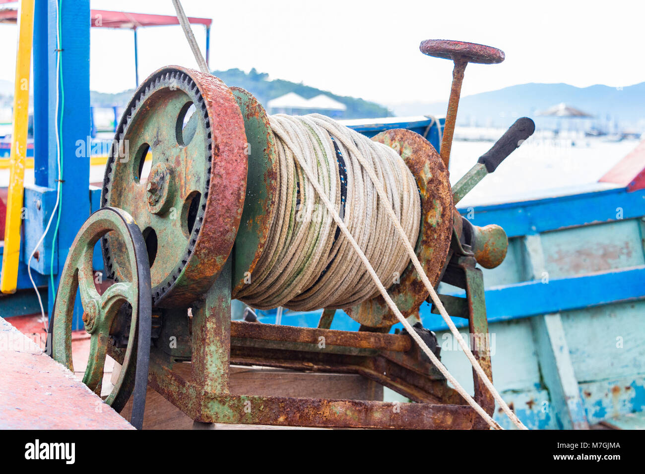 An old manual oxided winch placed on a fishing wooden boat in Porto Belo, Brazil. Stock Photo