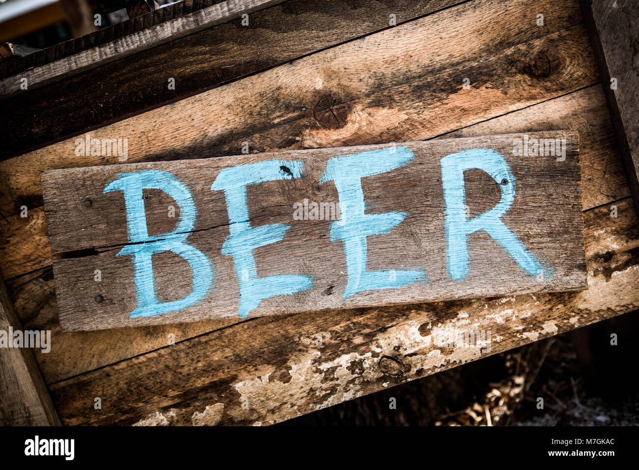 Beer sign in blue paint on weathered wooden board nailed to old box in close-up Stock Photo
