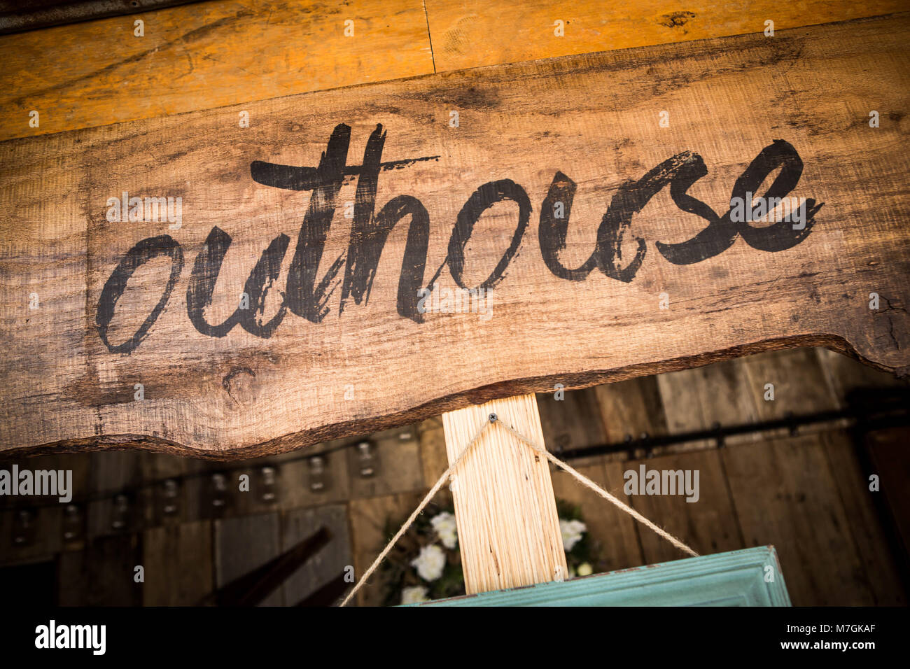 Black handwritten Outhouse sign on unpainted wooden board in close-up Stock Photo
