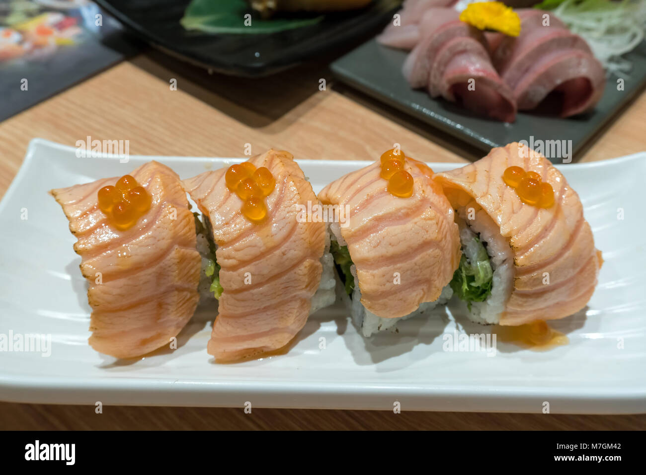 Seared Fresh Raw Salmon Sushi Nigiri Roll with fish roe on white plate closeup macro Stock Photo