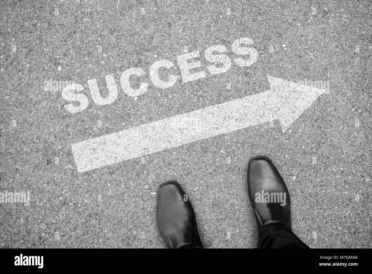 Businessman in black shoes standing in front of direction sign to success on the concrete floor Stock Photo