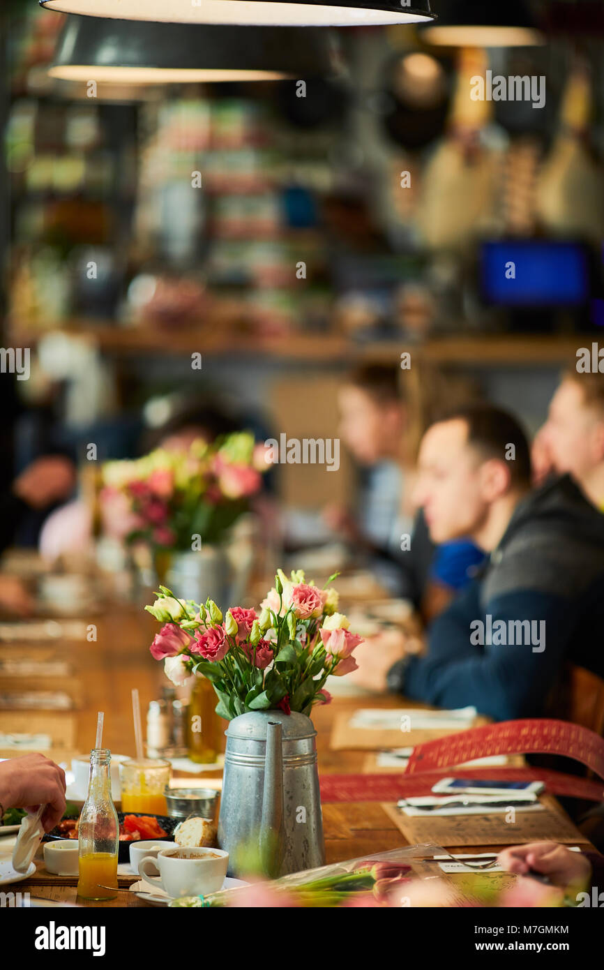 Table with flowers and people setting around Stock Photo