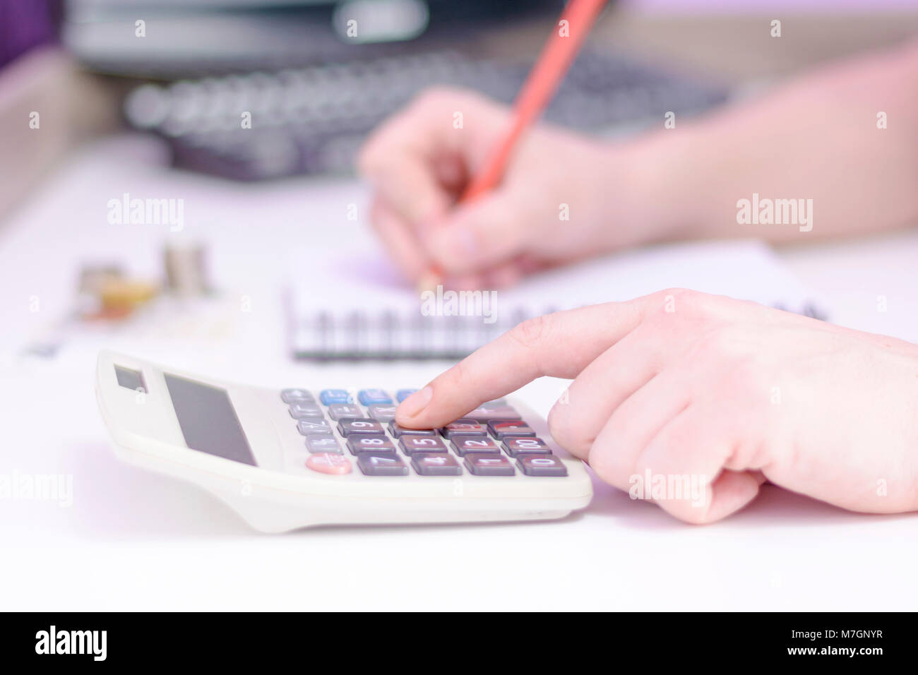 Photo of a hand counting on a calculator and holding a red pencil. Close up of a man counting on a calculator. Financial data analizing. Stock Photo