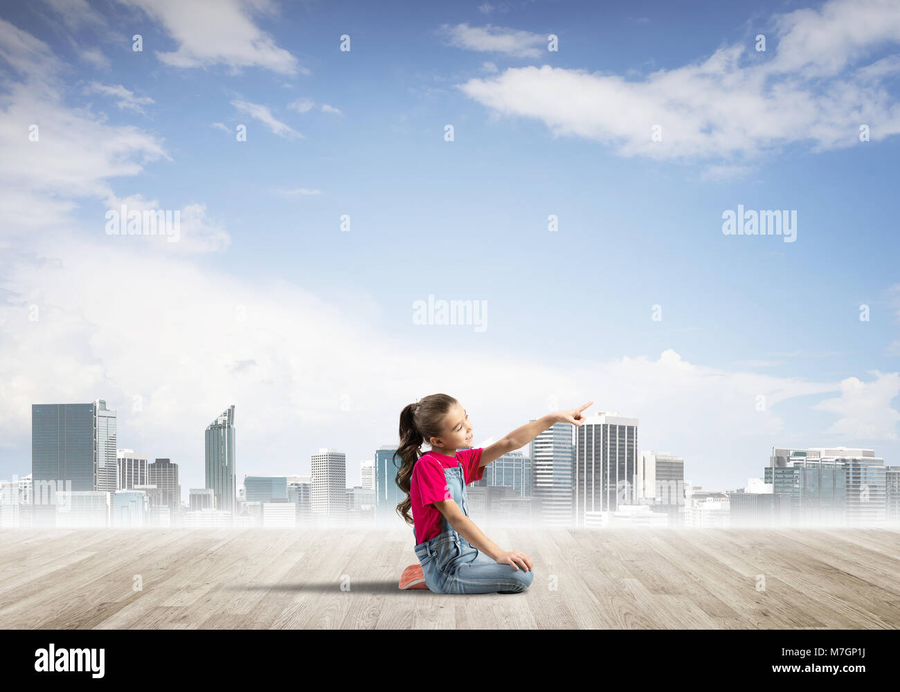 Cute kid girl sitting on wooden floor and pointing with finger Stock ...