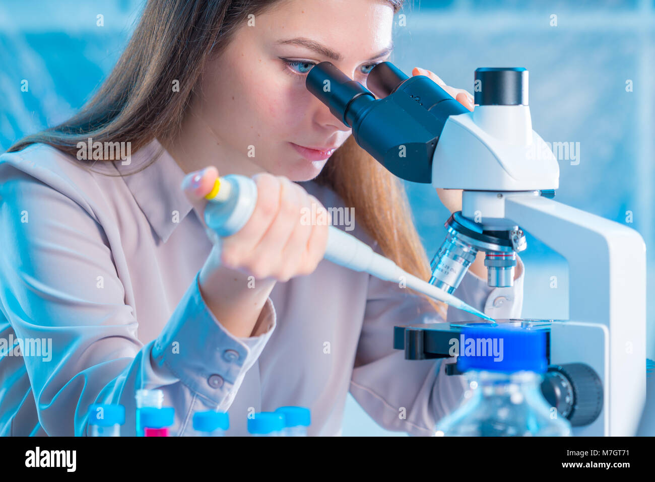 Lab Helpers laboratory assistant with a pipette and a microscope in the laboratory ...