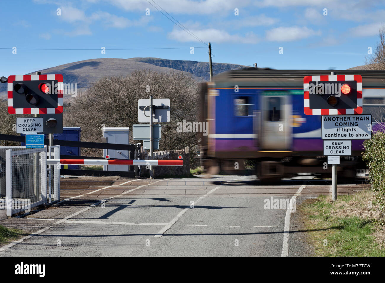 An Northern rail sprinter train crosses the automatic half barrier level crossing at Green road, Millom, Cumbria Stock Photo