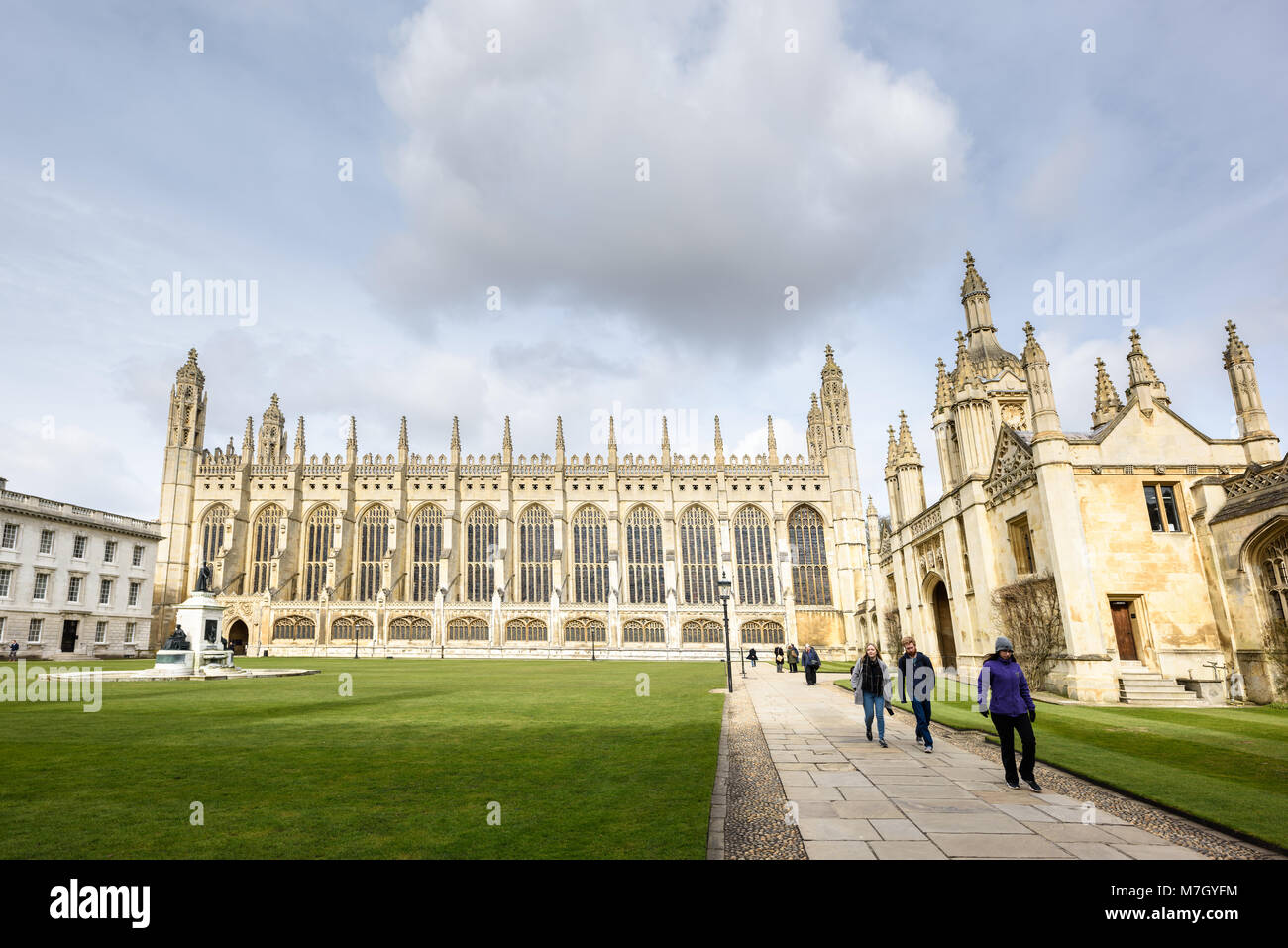 Students walk along a path next to the Front Court lawn at King's college, university of Cambridge, England, with the chapel in the centre, the Gate H Stock Photo