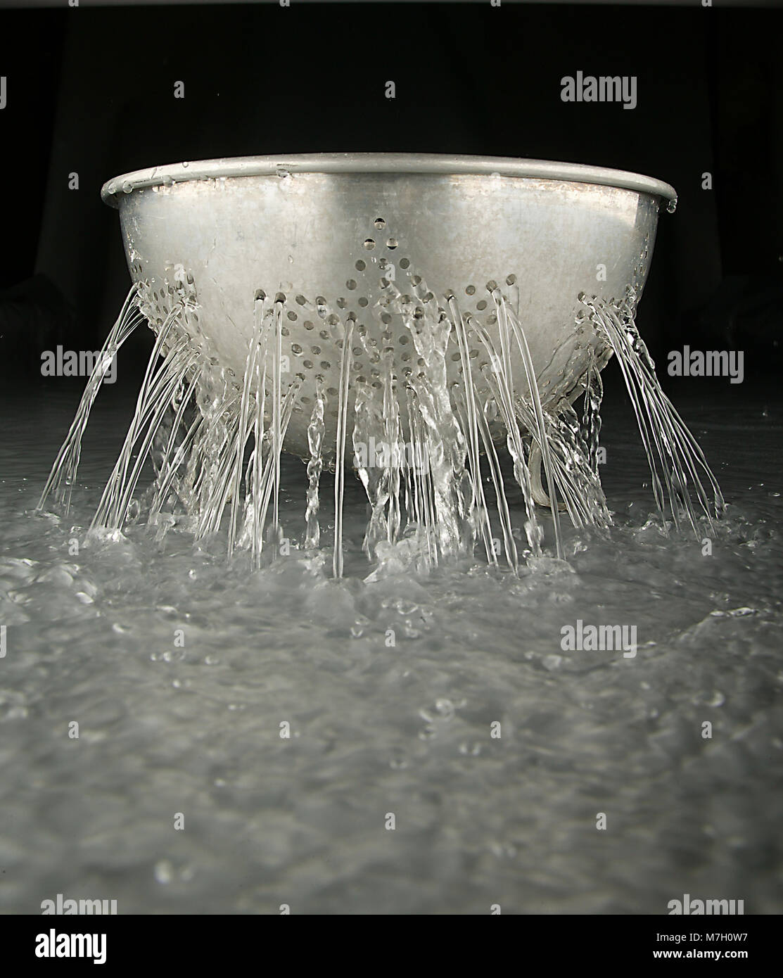 Colander with water flowing thru the holes Stock Photo Alamy