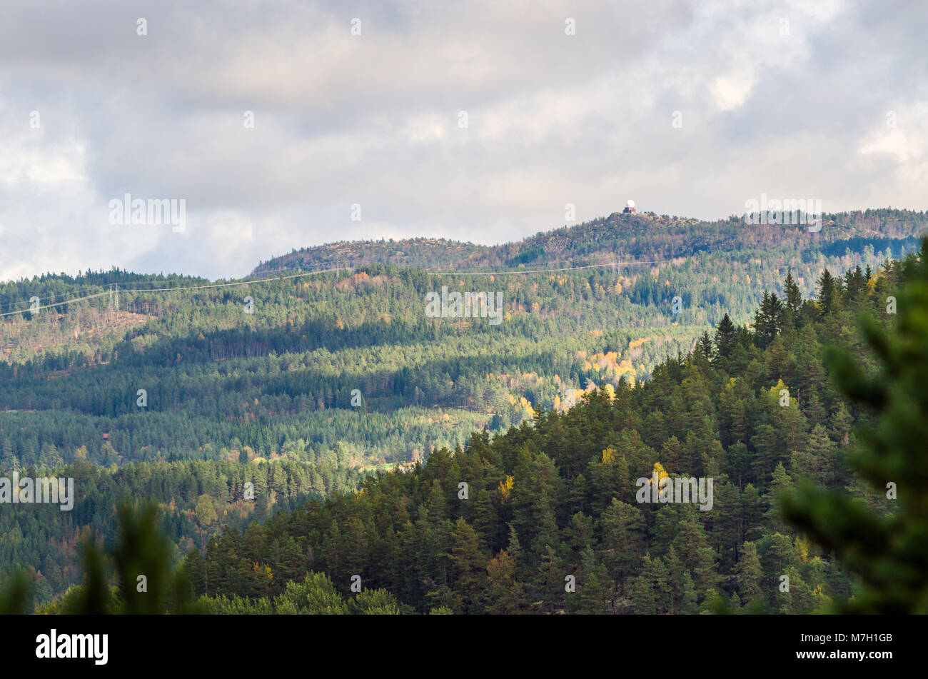 Landscape of central Norway midland with radar tower and low mountains covered by forest. Evje, middle of Norway. Stock Photo