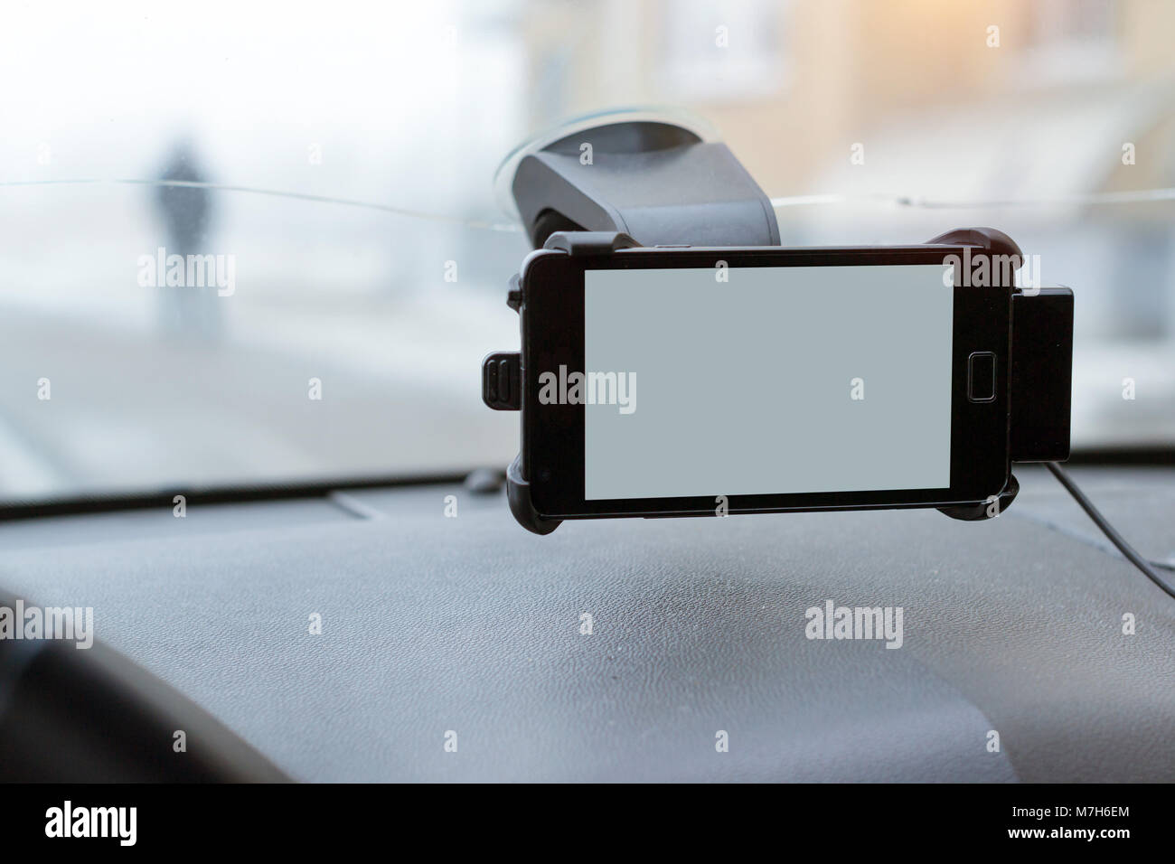 Car smartphone holder with phone attached to the windscreen of automobile. Accessories for vehicles, for ease of control a car in the way. Phone holde Stock Photo