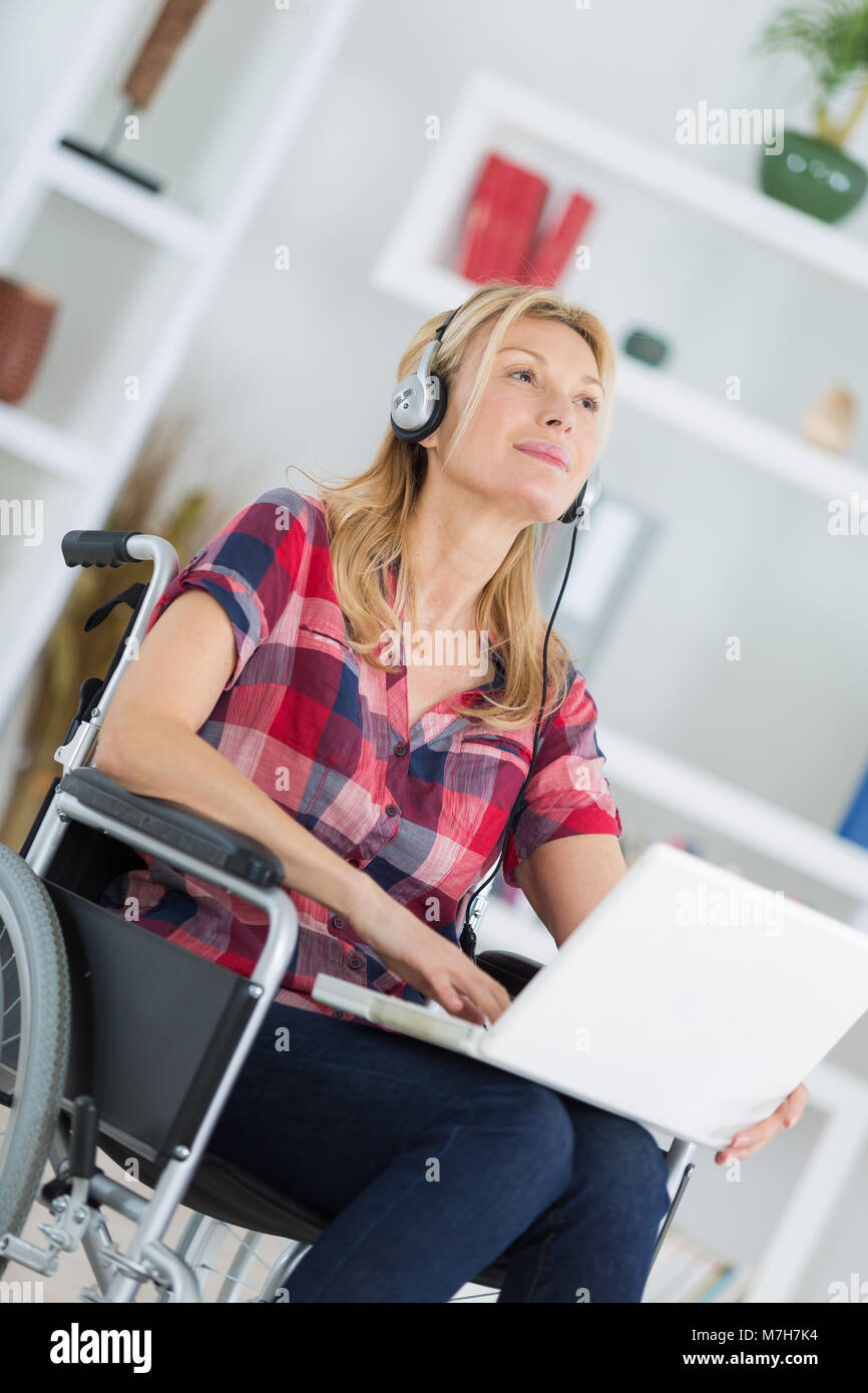 disabled woman in wheelchair with laptop and headphones Stock Photo - Alamy