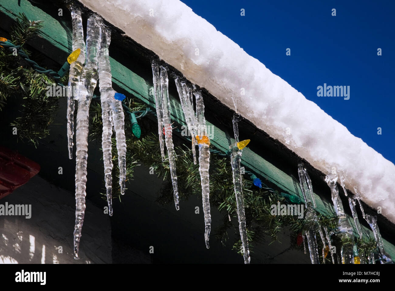 Snow And Ice With Christmas Lights And Icicles Hanging From The Eaves Stock Photo Alamy