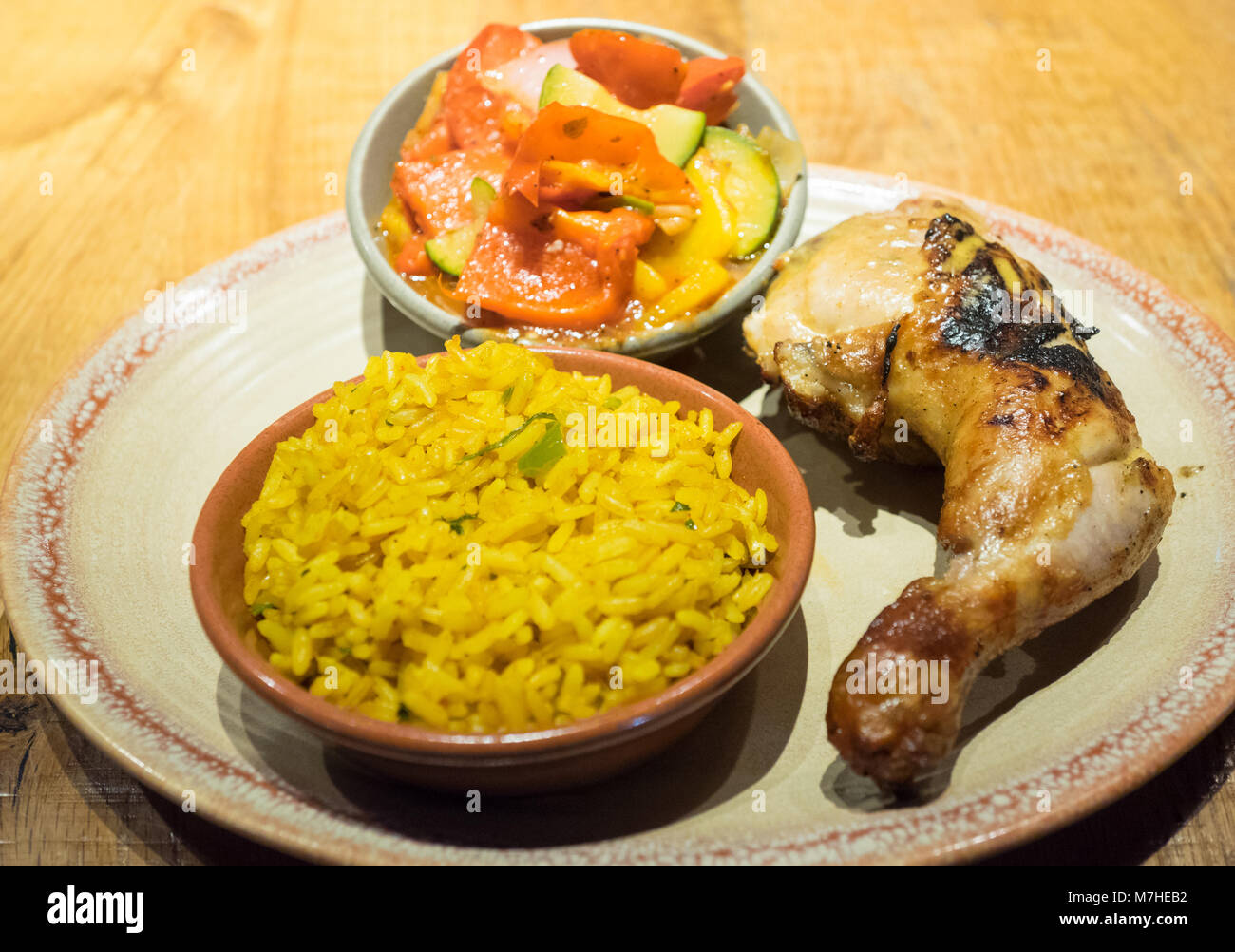 Peri-peri quarter chicken with sides of spiced rice and peri-peri vegetables from Nando's, a casual dining chain that originates from South Africa. Stock Photo