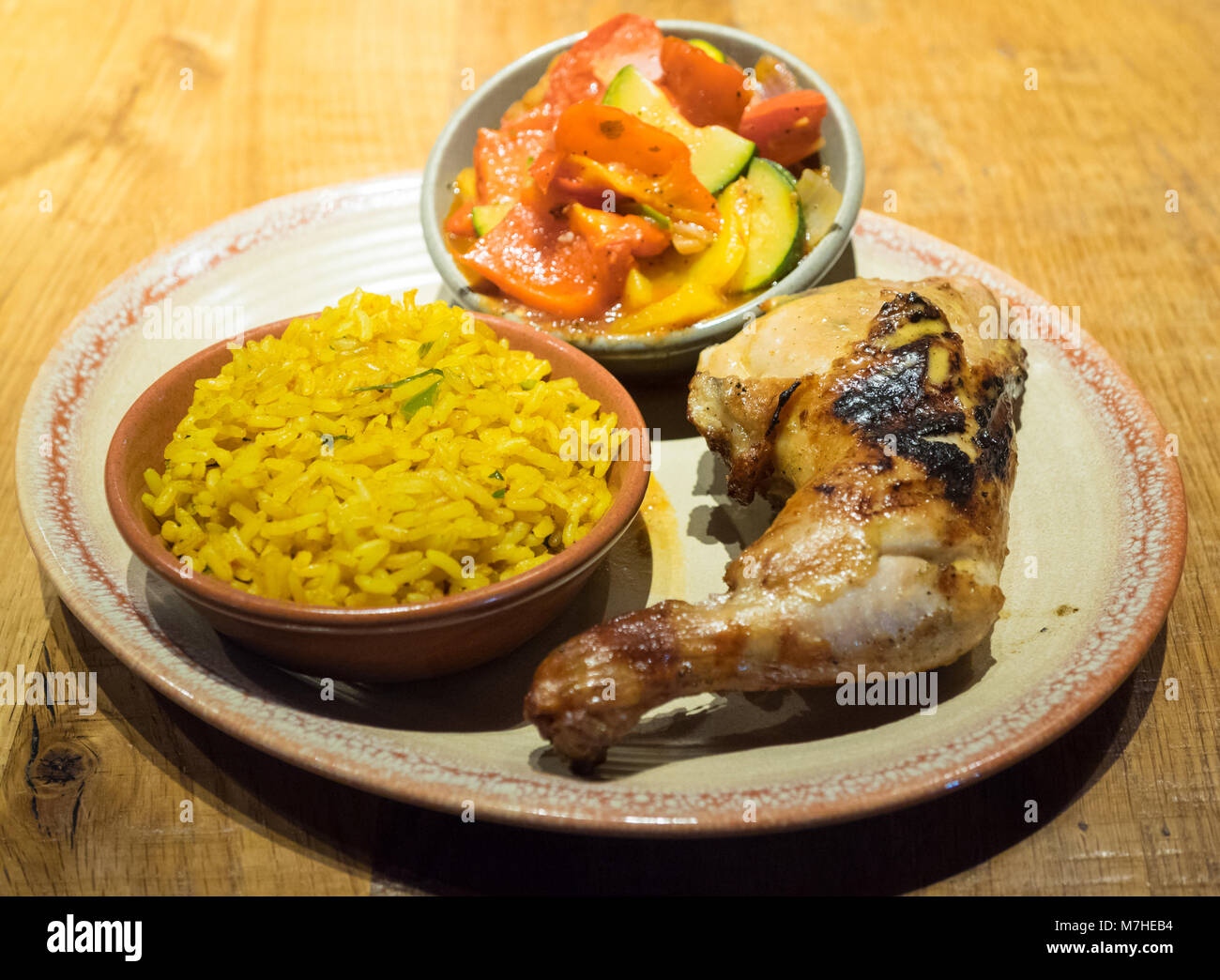 Peri-peri quarter chicken with sides of spiced rice and peri-peri vegetables from Nando's, a casual dining chain that originates from South Africa. Stock Photo