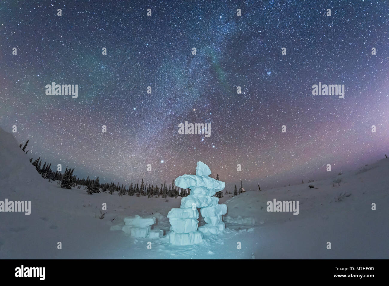 Milky Way and winter stars over a mock-up inukshuk figure made of snow, Canada. Stock Photo