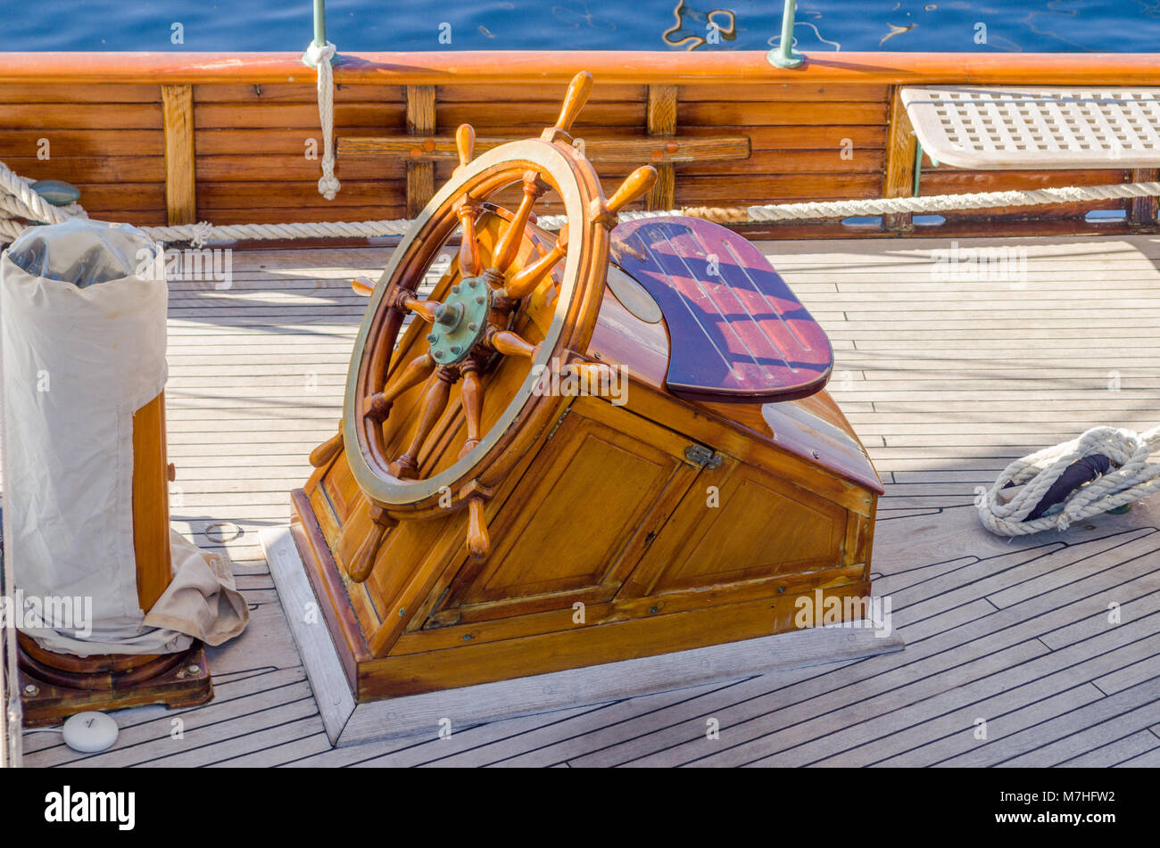 Helmsman site withe wooden ship's wheel on board of oldtimer sailing yacht in Oslo harbour, Oslo, Norway. Stock Photo