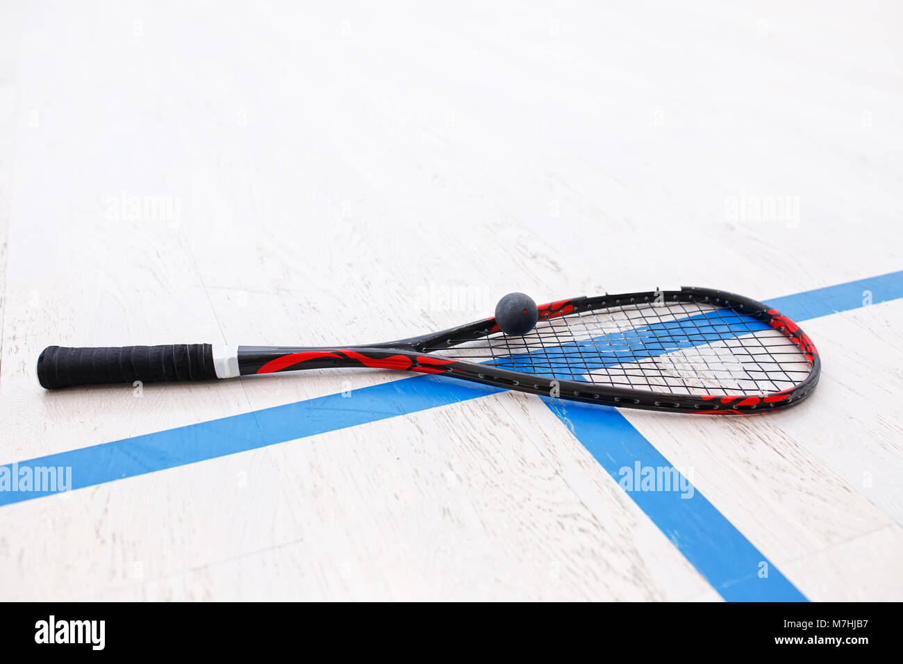 squash racket and ball on the wooden floor. Racquetball equipment on