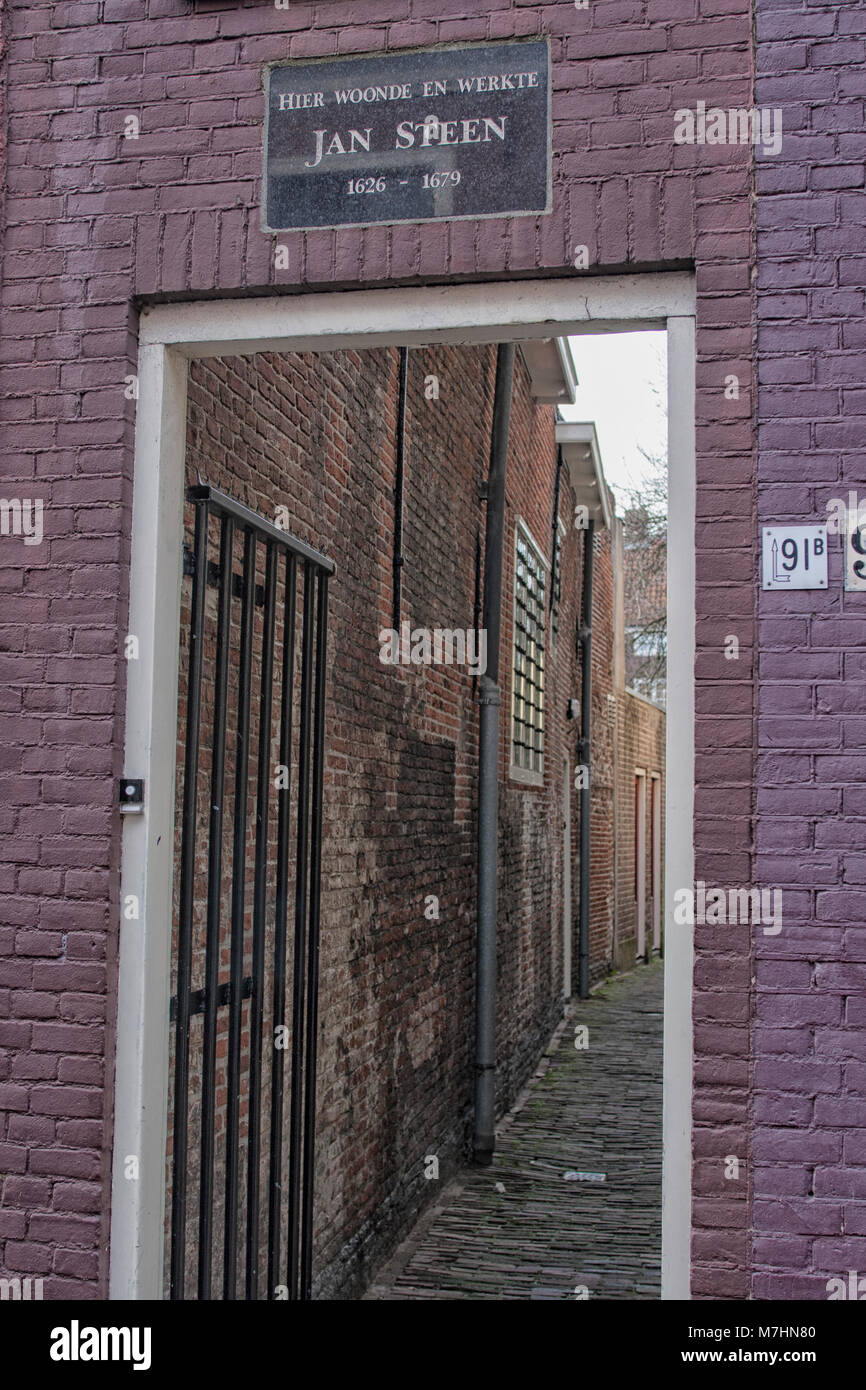 Plaque in wall in front of an alley with Dutch text: Here lived and worked Jan Steen. This gate was (and is) the entrance to houses for ages. Once the Stock Photo