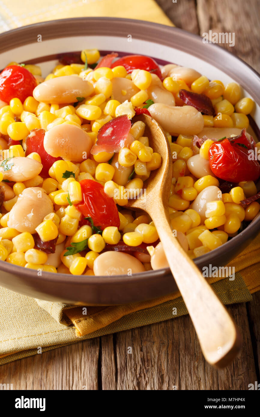 Traditional succotash of corn, butter beans, tomatoes and bacon close up in a bowl on the table. vertical Stock Photo