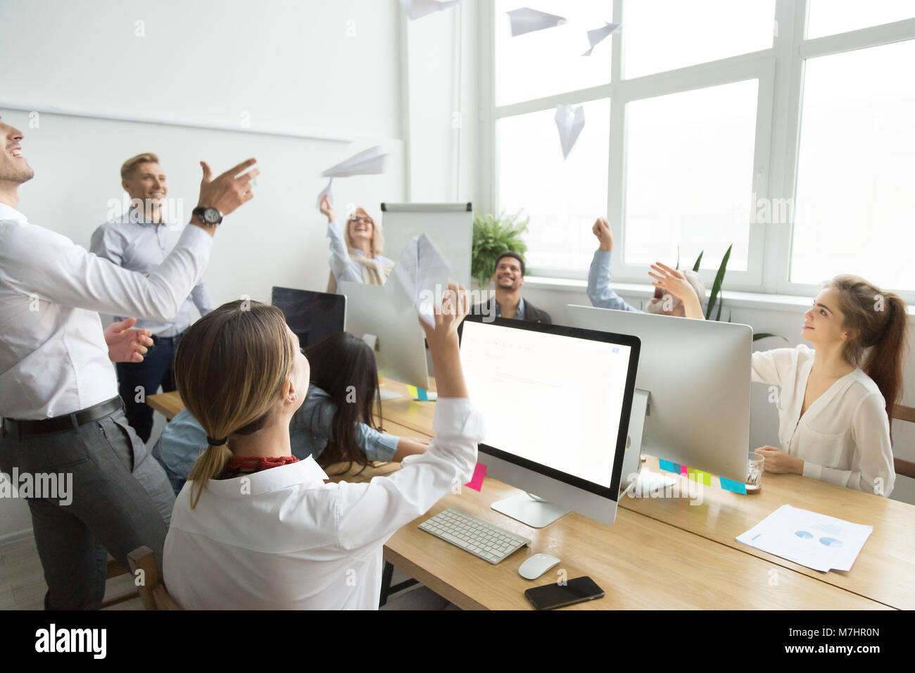 Multiracial motivated employees launching paper planes together, Stock Photo