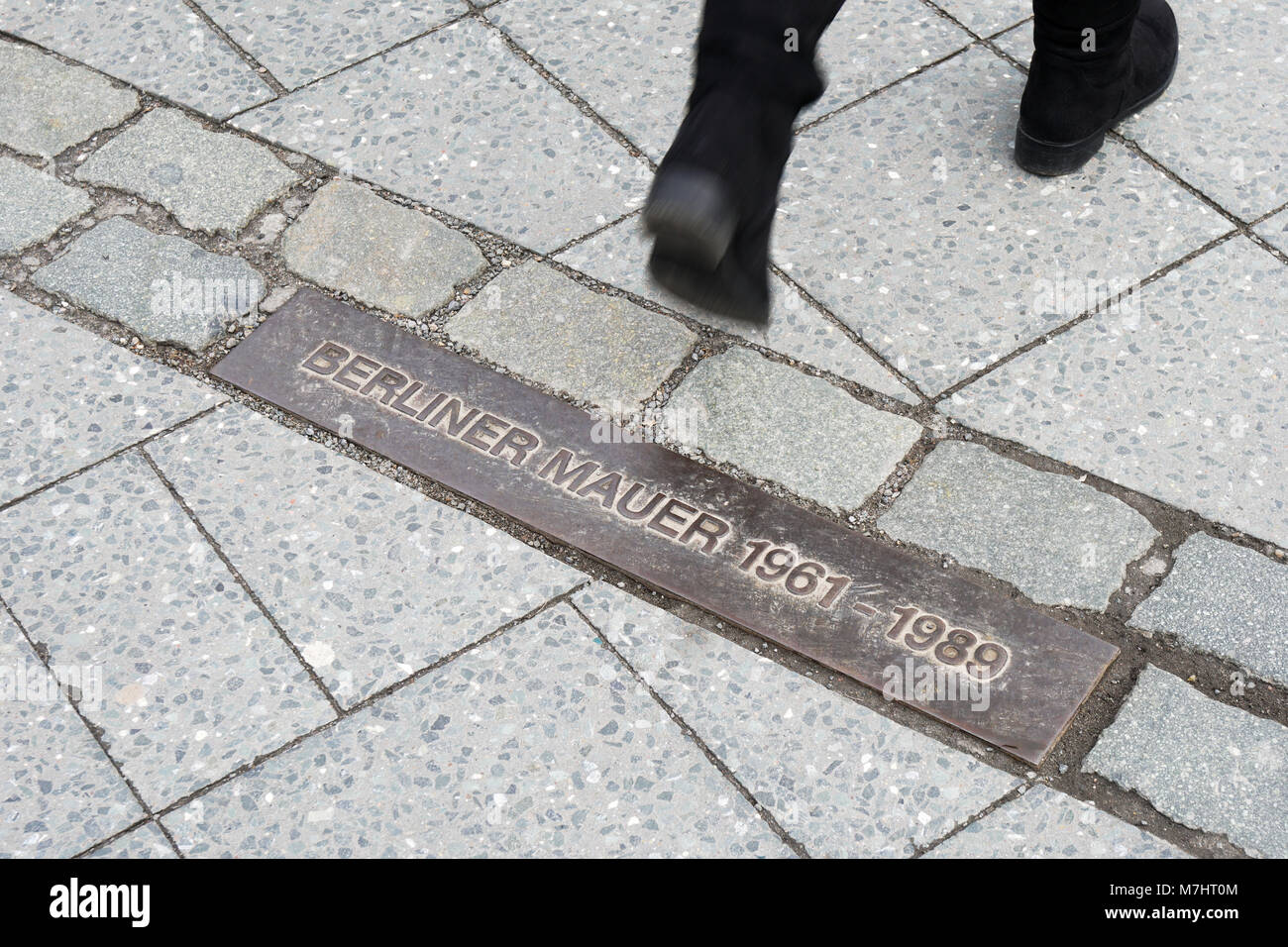 pedestrian walking across commemorative plaque for Berlin Wall Stock Photo