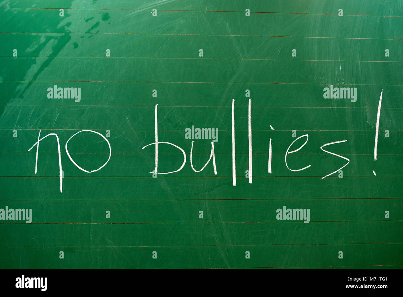 The words NO BULLIES written on the green school board with a white chalk background Stock Photo