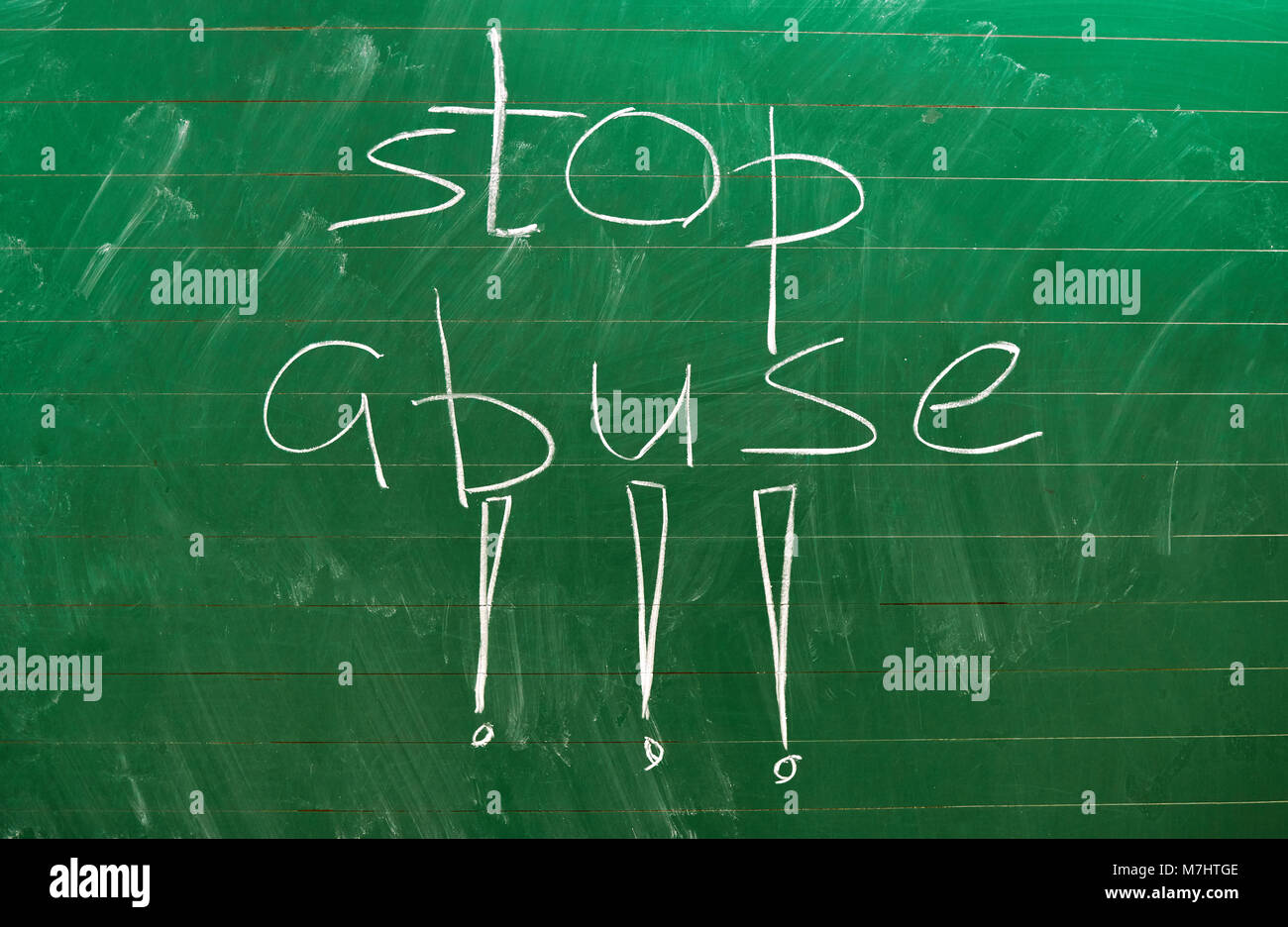 The words STOP ABUSE written on the green school board with a white chalk background Stock Photo