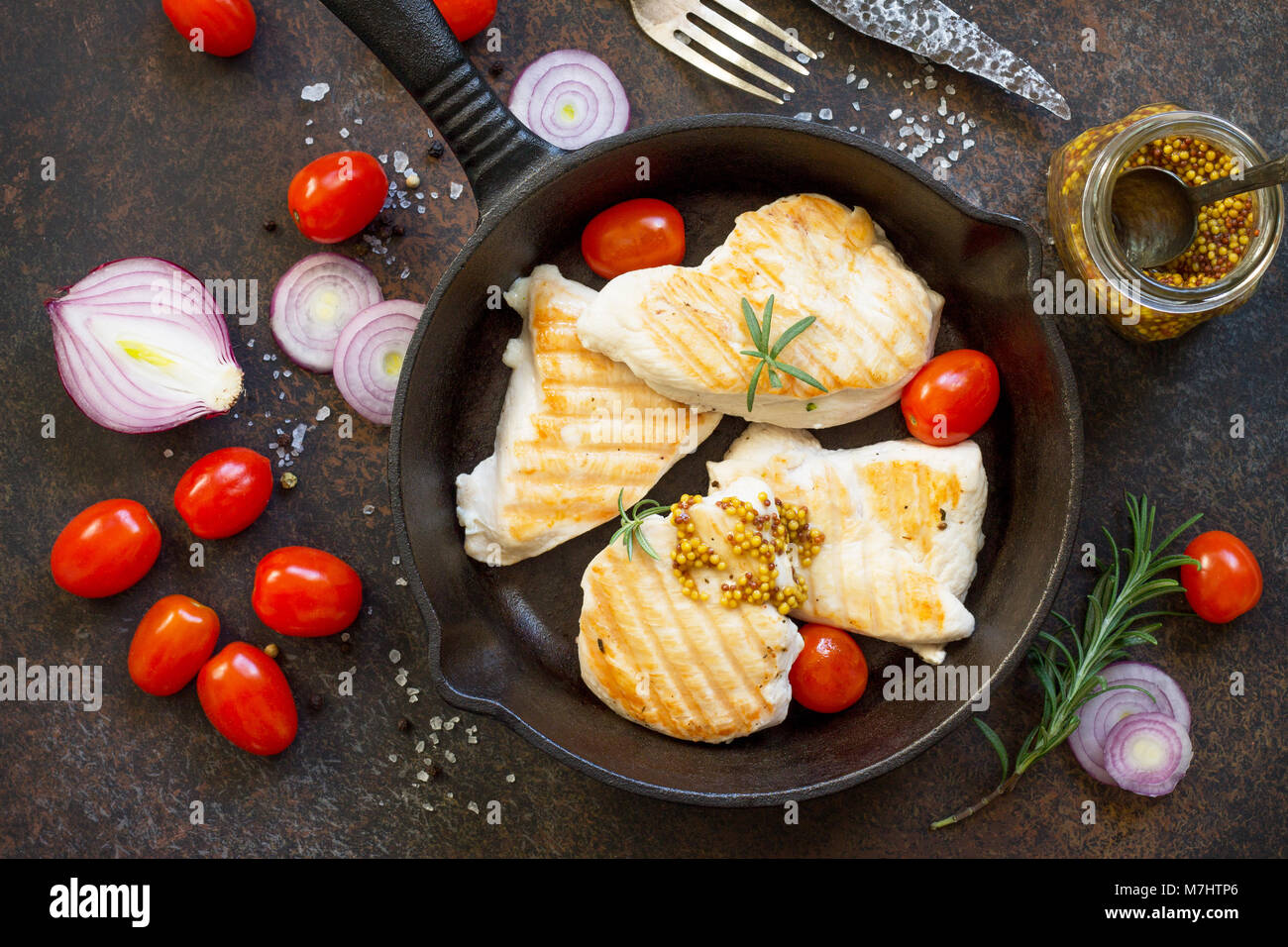 Grilled chicken fillet and various vegetables on a cast-iron frying pan. Copy space, top view flat lay background. Stock Photo