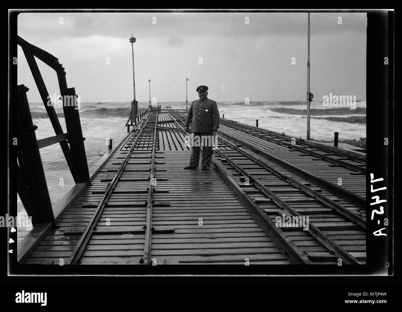 This image shows the jetty in Tel Aviv with a guard posted, reflecting ...