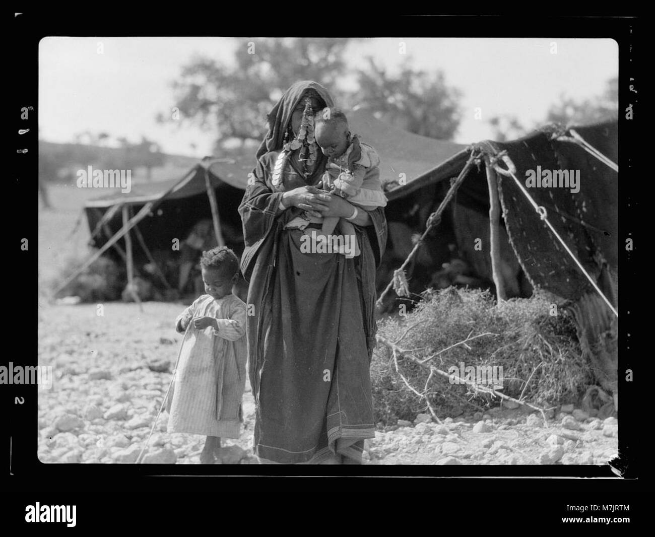 A photograph of a mother and her children standing before their tent ...