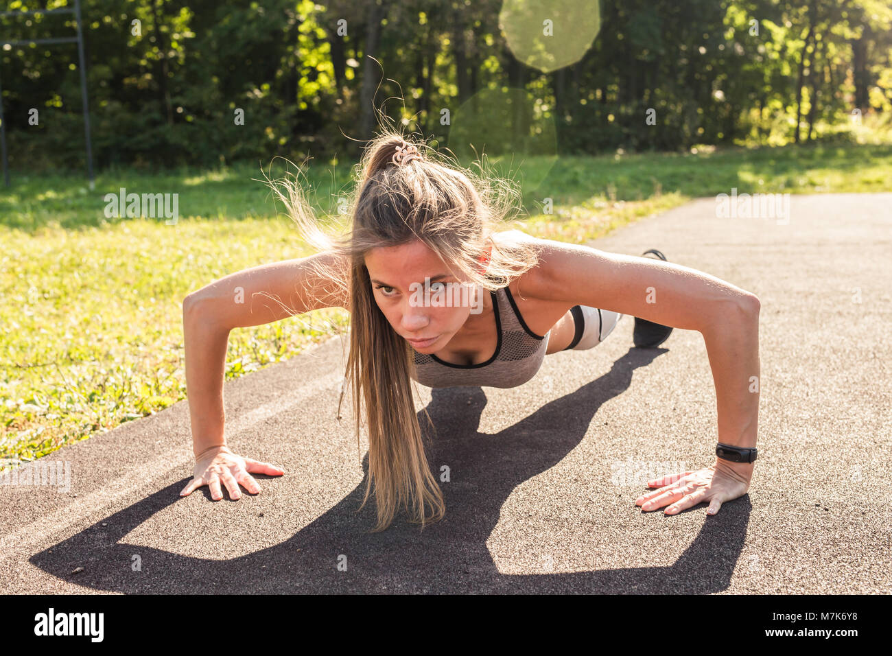 Fitness woman doing push-ups during outdoor cross training workout ...