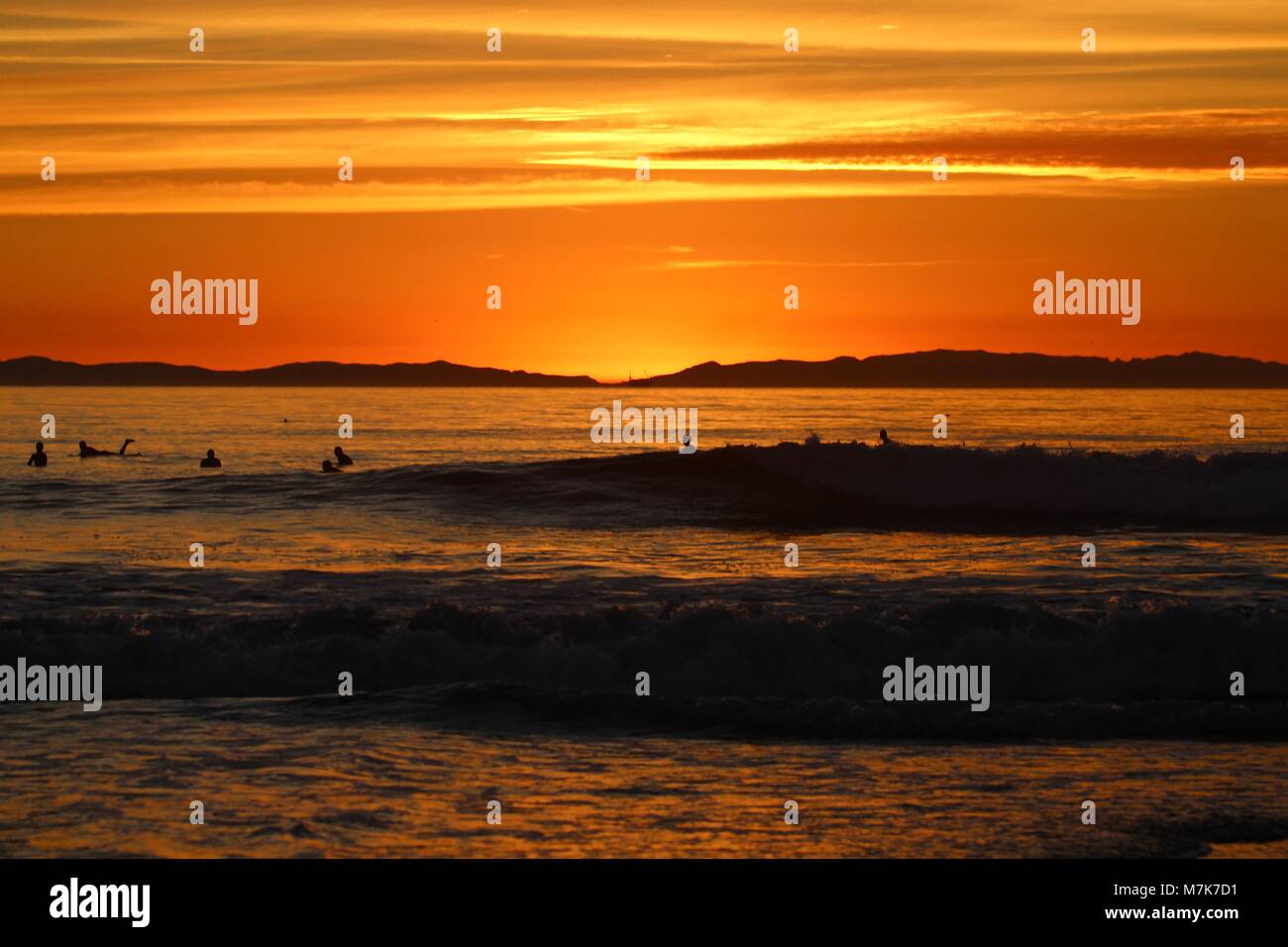 Orange Sunset with silhouettes of surfers Stock Photo