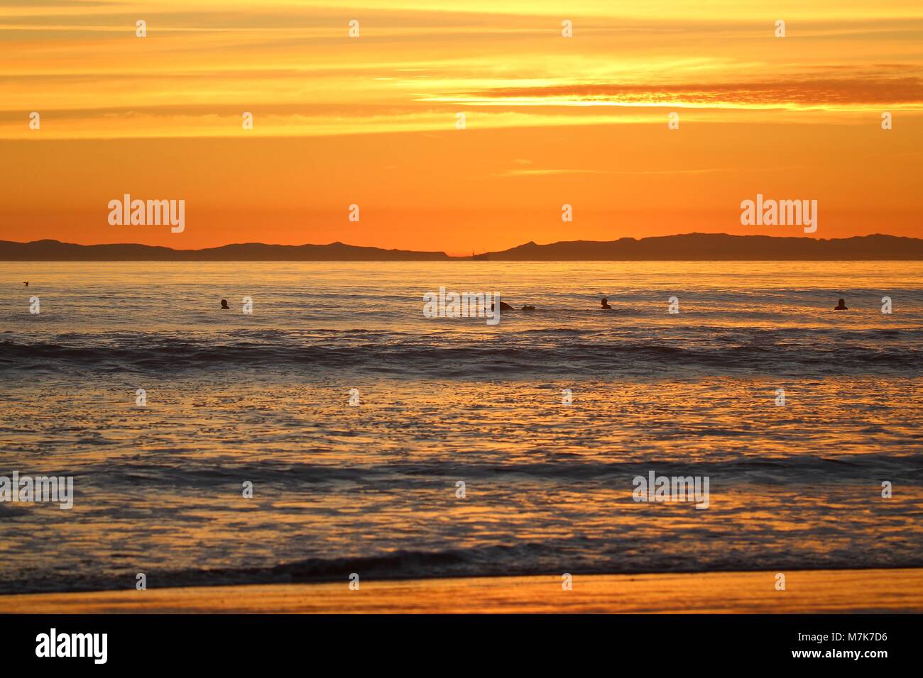 Orange Sunset with silhouettes of surfers Stock Photo