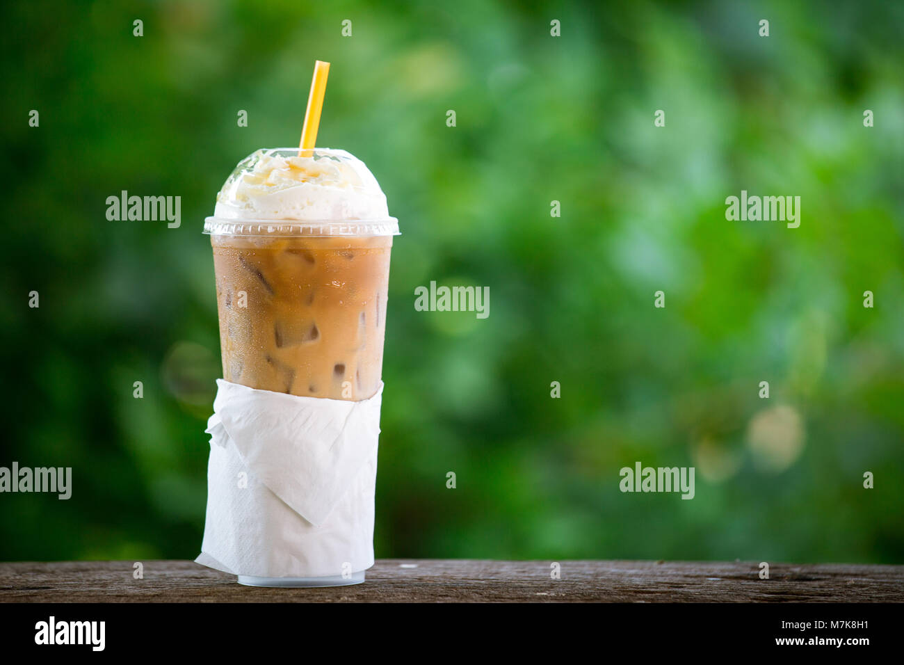 https://c8.alamy.com/comp/M7K8H1/iced-coffee-with-whipped-cream-in-plastic-cup-on-the-garden-table-M7K8H1.jpg