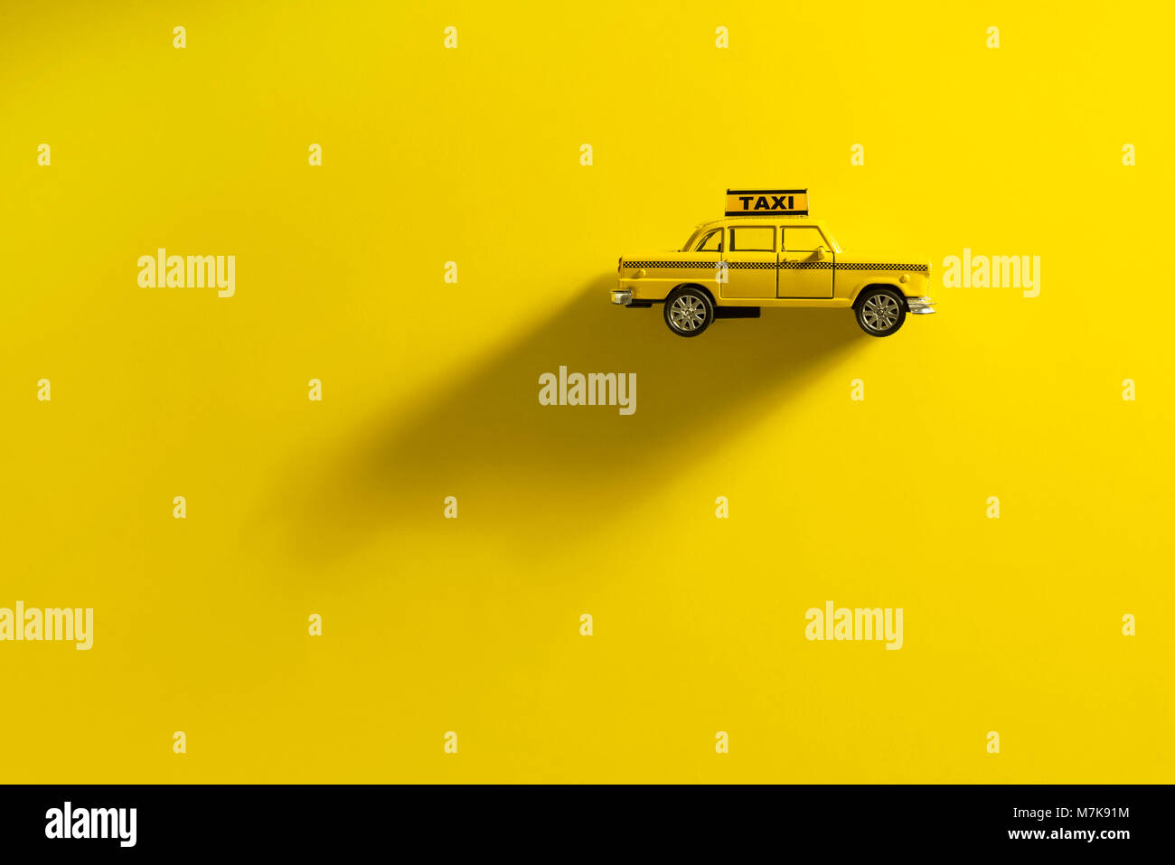 Yellow toy taxi car on a yellow background with a long shadow Stock Photo