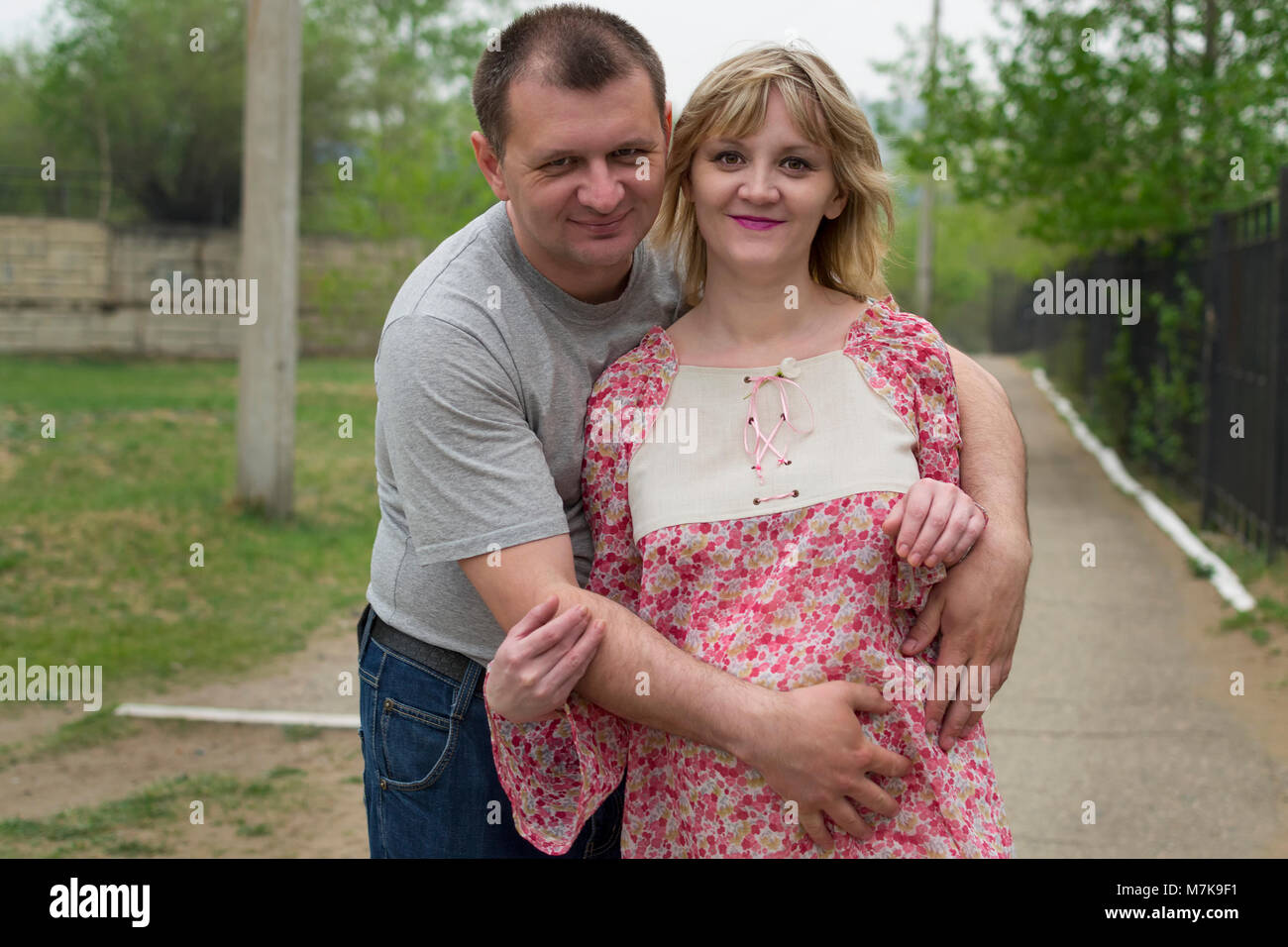 Pregnant couple happy touching belly with hands. Pregnant young woman walking with her husband Stock Photo