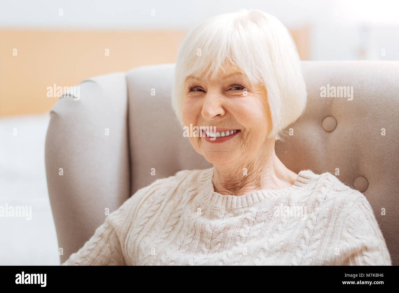 Adorable cute aged woman feeling happy while sitting and smiling Stock Photo