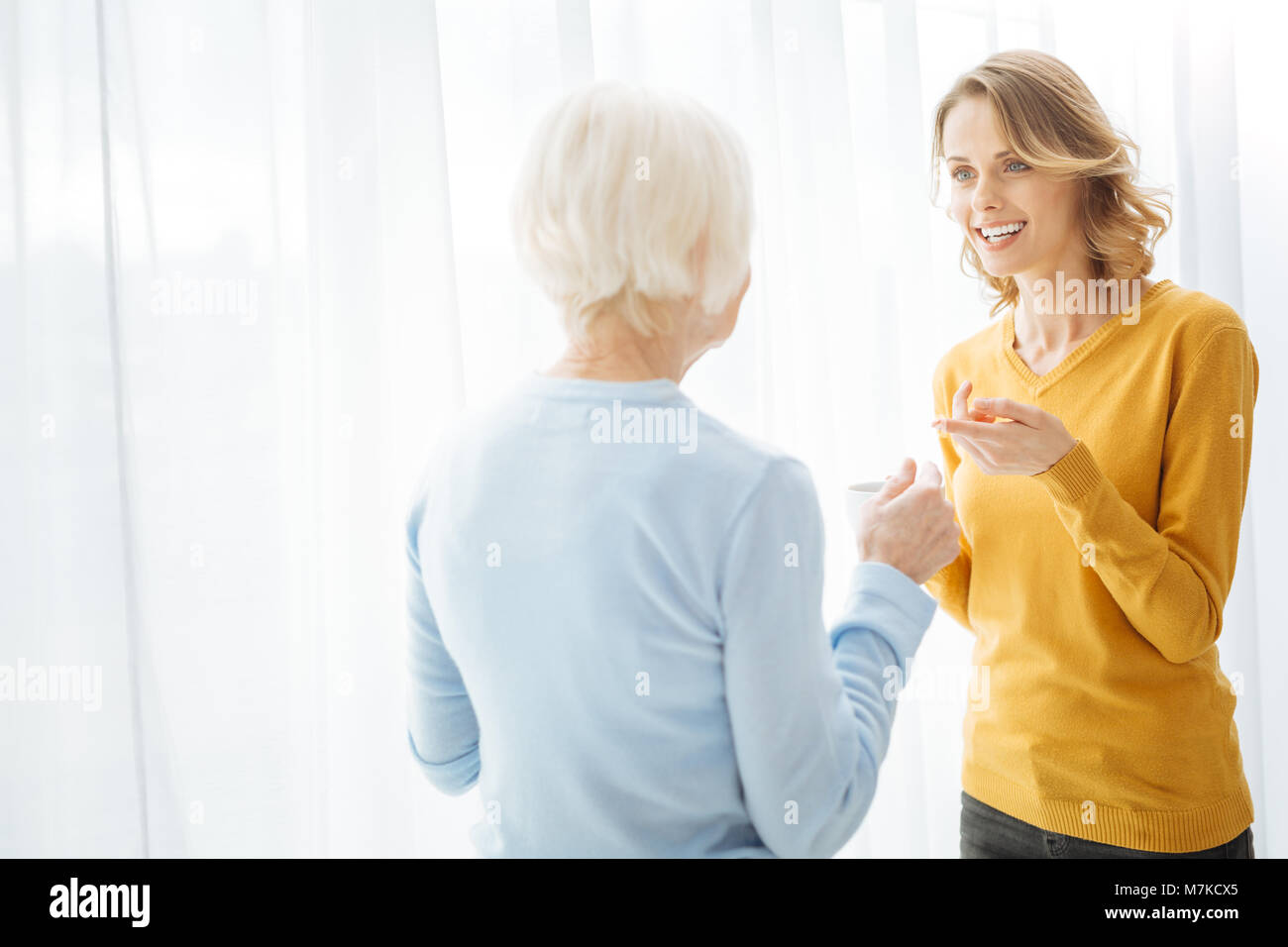 Two emotional women being involved in a lovely talk and smiling Stock Photo