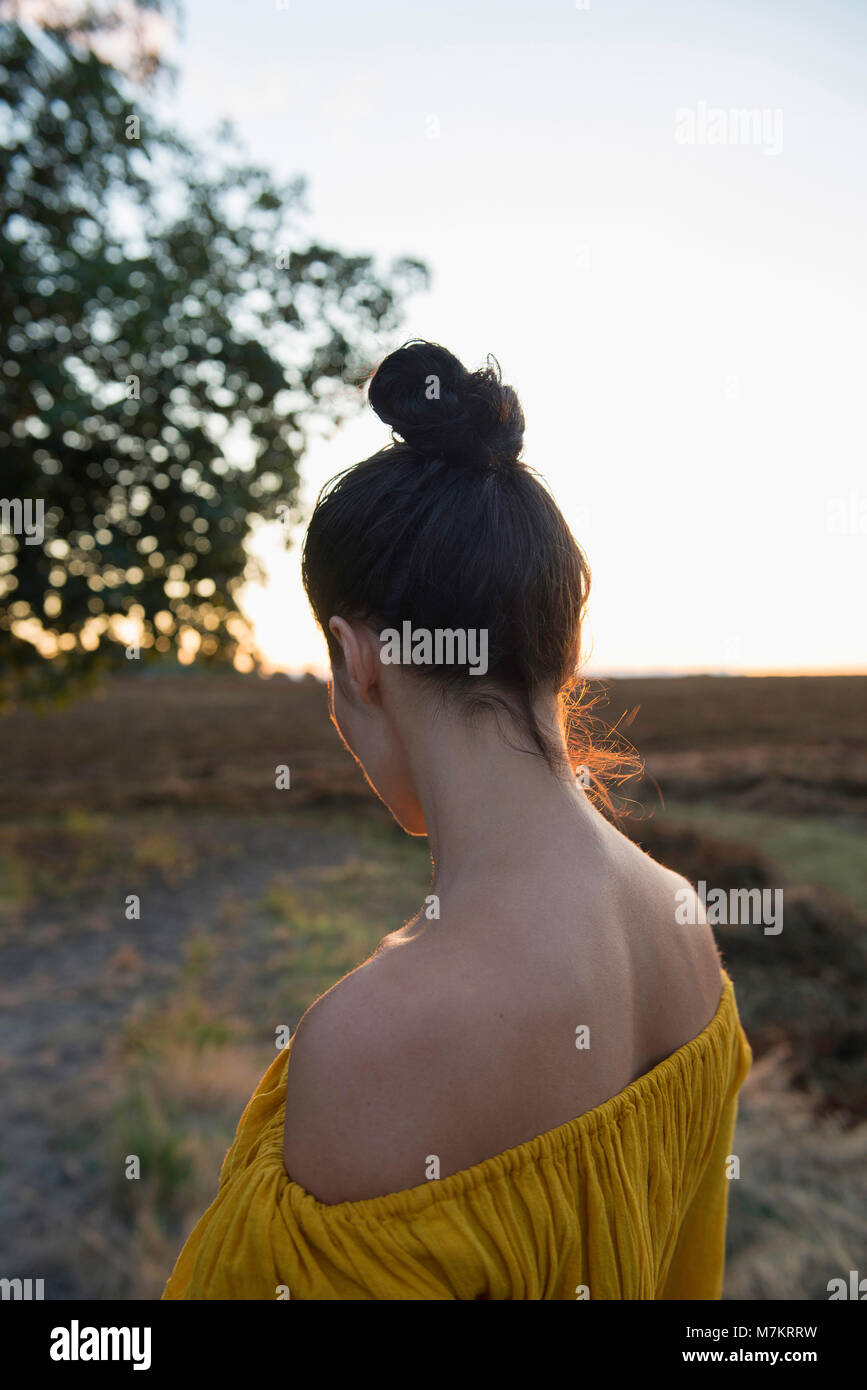 A woman standing in a rural environment, photographed from behind. Stock Photo
